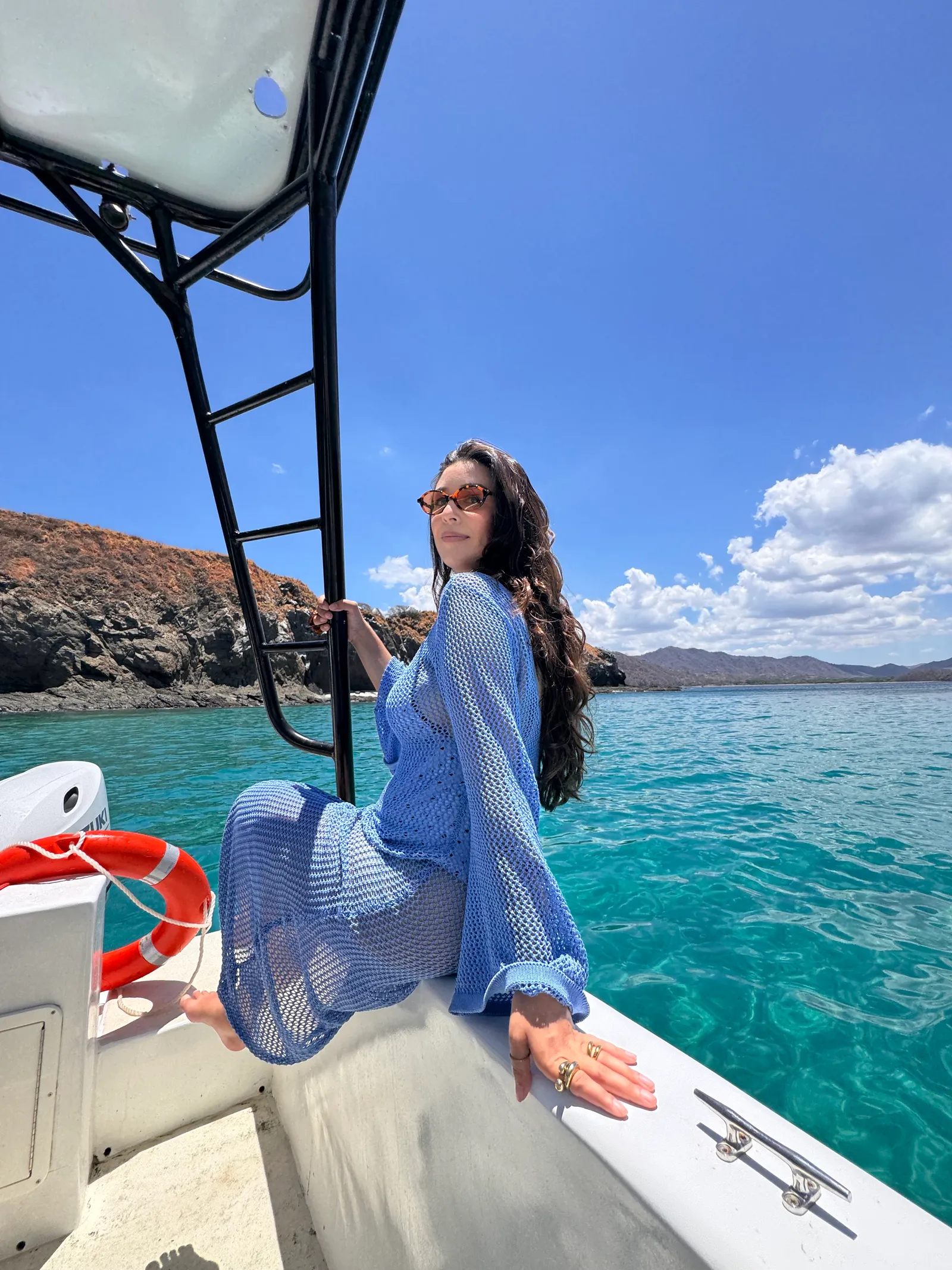 A guest on the bow of the Malix boat over clear turquoise water off Playa Flamingo